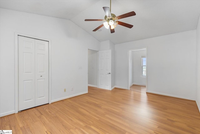 unfurnished bedroom with ceiling fan, a closet, light hardwood / wood-style floors, and vaulted ceiling