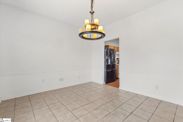 tiled empty room featuring an inviting chandelier