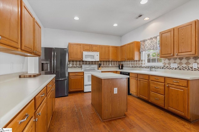 kitchen featuring sink, a center island, white appliances, and light hardwood / wood-style flooring