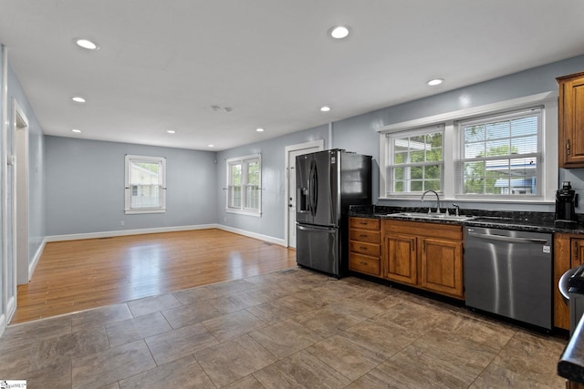 kitchen featuring dark stone countertops, appliances with stainless steel finishes, hardwood / wood-style floors, and a wealth of natural light