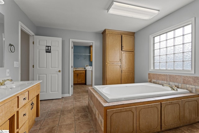 bathroom featuring tiled tub, vanity, tile patterned flooring, and washer / dryer