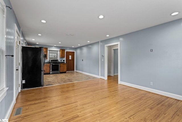 kitchen with fridge, stainless steel stove, and light hardwood / wood-style flooring