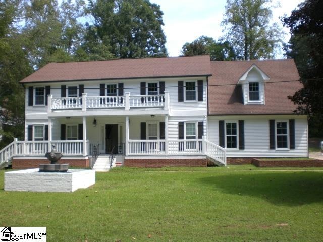 colonial home featuring a front lawn and a balcony