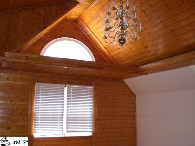 details with wooden ceiling, an inviting chandelier, wooden walls, and beam ceiling