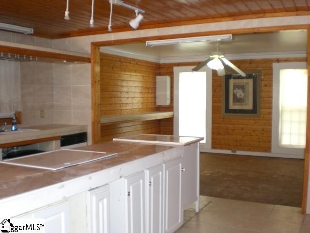 kitchen featuring white cabinets, wood ceiling, wood walls, and light tile patterned flooring