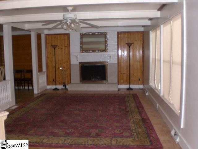 unfurnished living room with ceiling fan and beamed ceiling