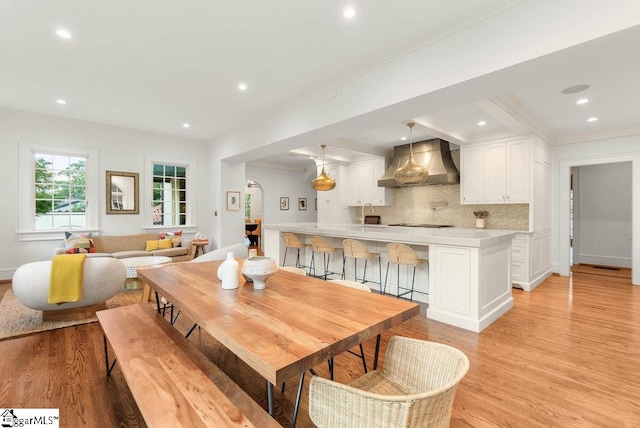 dining room with crown molding and light hardwood / wood-style flooring