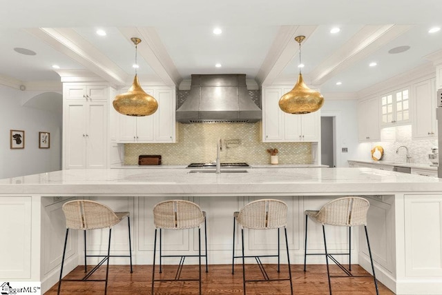 kitchen featuring tasteful backsplash, a spacious island, wall chimney exhaust hood, and white cabinetry