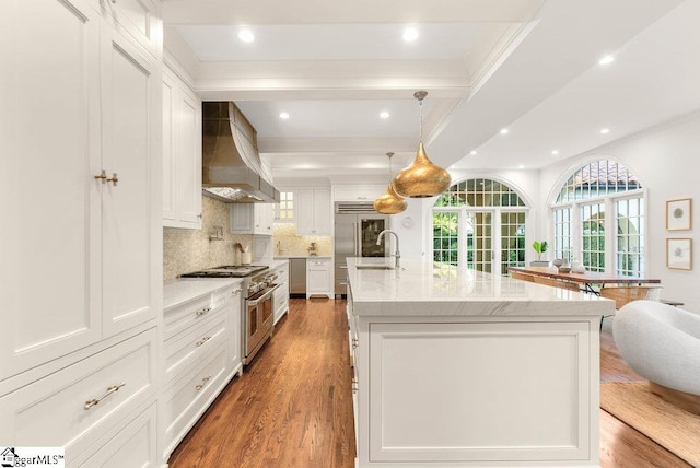 kitchen with light hardwood / wood-style flooring, custom range hood, double oven range, a kitchen island with sink, and white cabinetry