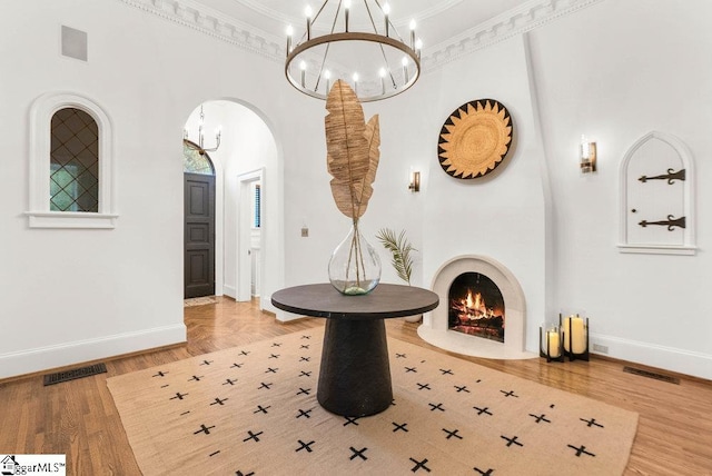 foyer entrance with a high ceiling, a large fireplace, light hardwood / wood-style floors, and crown molding