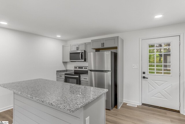 kitchen with gray cabinets, a center island, stainless steel appliances, and light hardwood / wood-style floors