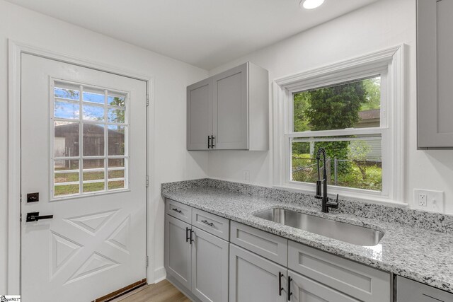 kitchen featuring light stone countertops, light hardwood / wood-style floors, and sink