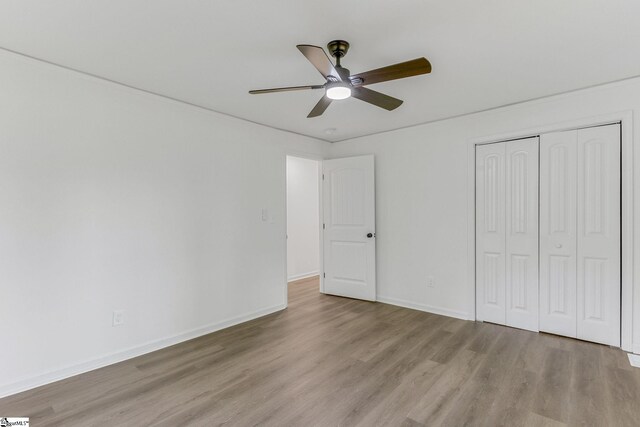 unfurnished bedroom featuring light hardwood / wood-style flooring, ceiling fan, and a closet