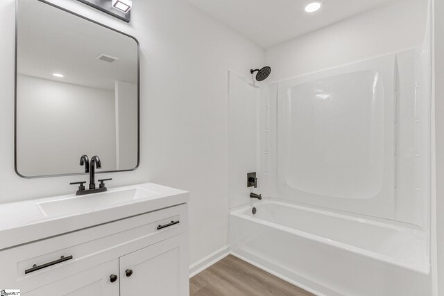 bathroom with vanity, hardwood / wood-style flooring, and washtub / shower combination