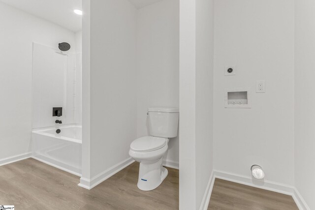 bathroom with toilet, hardwood / wood-style flooring, and  shower combination