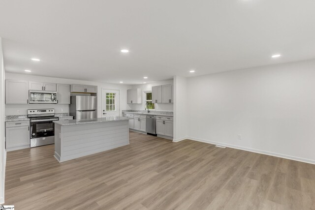 kitchen featuring appliances with stainless steel finishes, light hardwood / wood-style flooring, a kitchen island, and sink