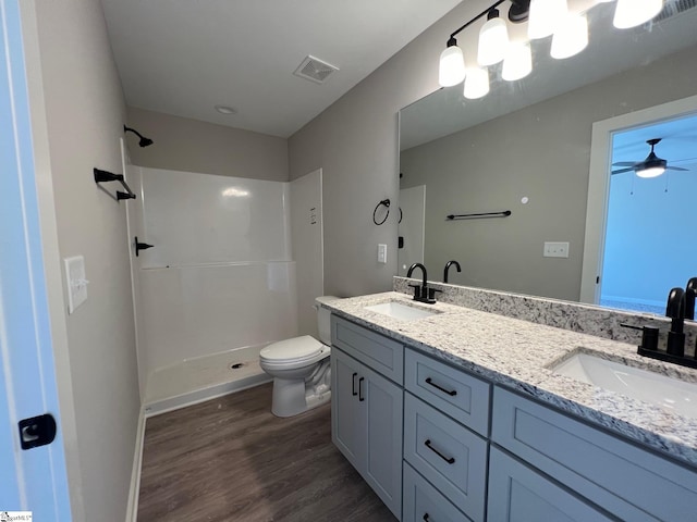 bathroom with hardwood / wood-style floors, vanity, ceiling fan, toilet, and walk in shower