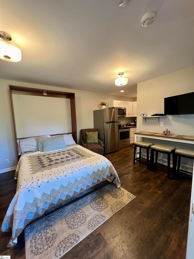 bedroom with stainless steel refrigerator and dark hardwood / wood-style floors