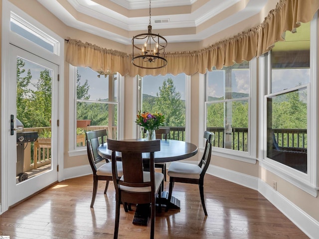 sunroom / solarium featuring a raised ceiling and an inviting chandelier