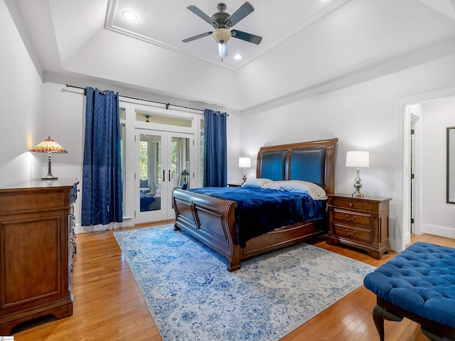 bedroom featuring light wood-type flooring, a raised ceiling, access to exterior, ceiling fan, and french doors