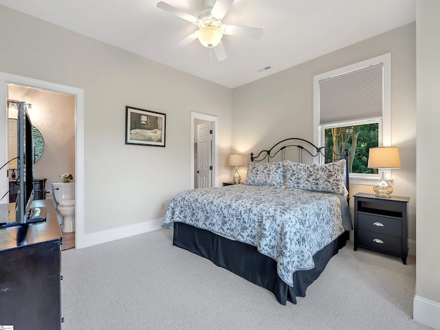 carpeted bedroom with ensuite bath and ceiling fan