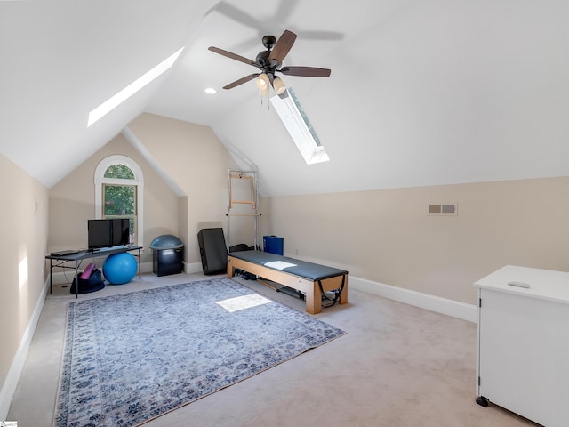 workout area with light colored carpet, vaulted ceiling with skylight, and ceiling fan