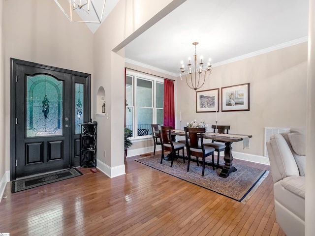 entryway with ornamental molding, high vaulted ceiling, an inviting chandelier, and dark hardwood / wood-style floors