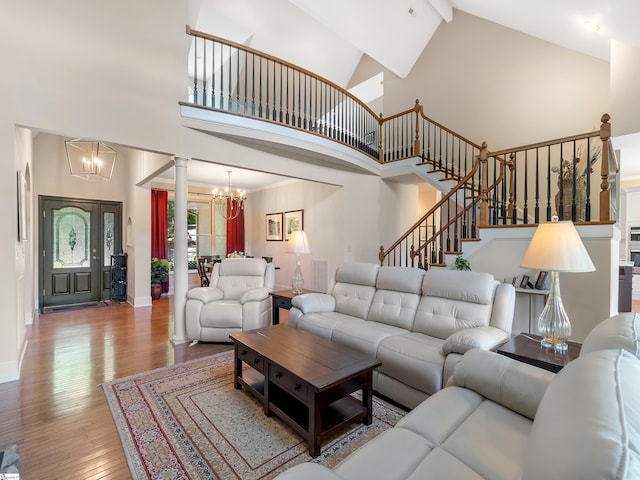 living room with beamed ceiling, high vaulted ceiling, hardwood / wood-style floors, an inviting chandelier, and ornate columns