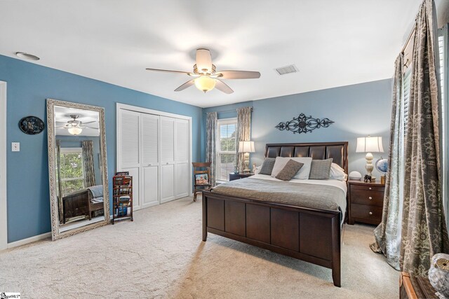 bedroom with multiple windows, light colored carpet, ceiling fan, and a closet