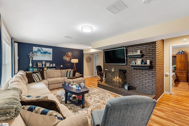 living room with a brick fireplace and hardwood / wood-style flooring