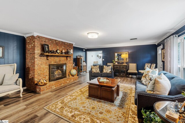 living room featuring light wood-type flooring, crown molding, and a fireplace