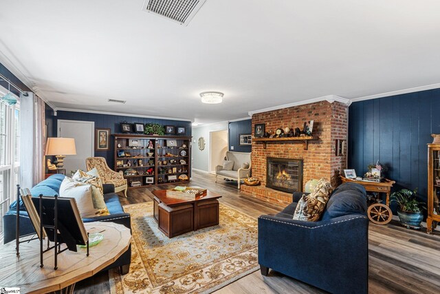 living room with wood-type flooring, a fireplace, crown molding, and wooden walls