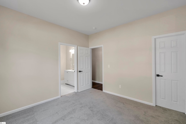 unfurnished bedroom featuring ensuite bathroom and light colored carpet