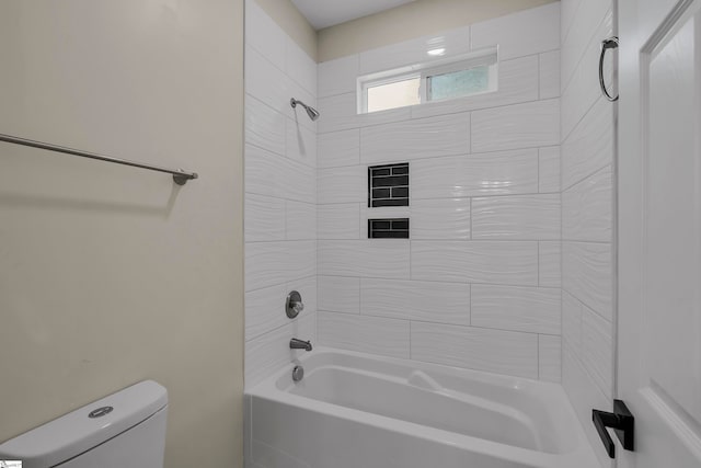 bathroom featuring tiled shower / bath combo and toilet