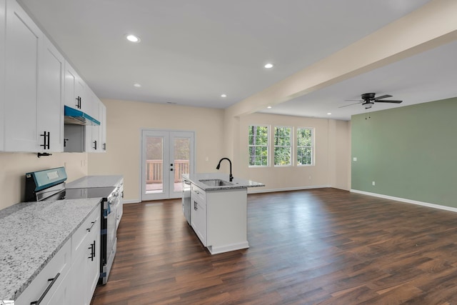 kitchen with sink, light stone countertops, dark wood-type flooring, appliances with stainless steel finishes, and a center island with sink