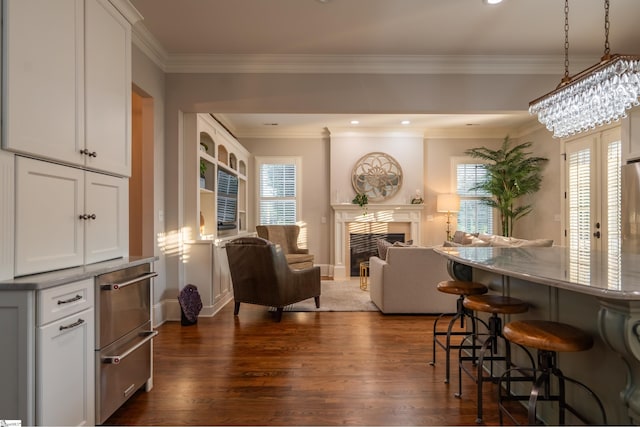 interior space featuring ornamental molding, a fireplace, dark wood finished floors, and baseboards