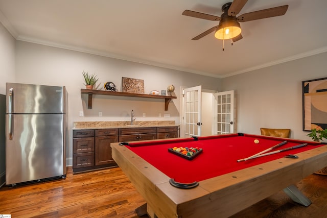 game room featuring wet bar, ornamental molding, a sink, and wood finished floors