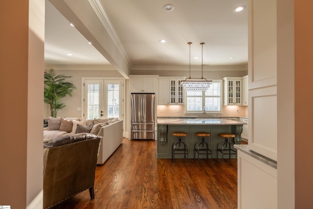 kitchen featuring freestanding refrigerator, open floor plan, plenty of natural light, and a breakfast bar area