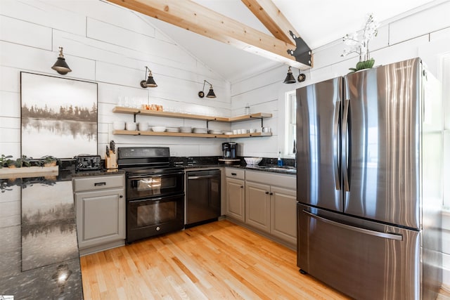 kitchen featuring dark stone countertops, appliances with stainless steel finishes, vaulted ceiling with beams, and light hardwood / wood-style floors