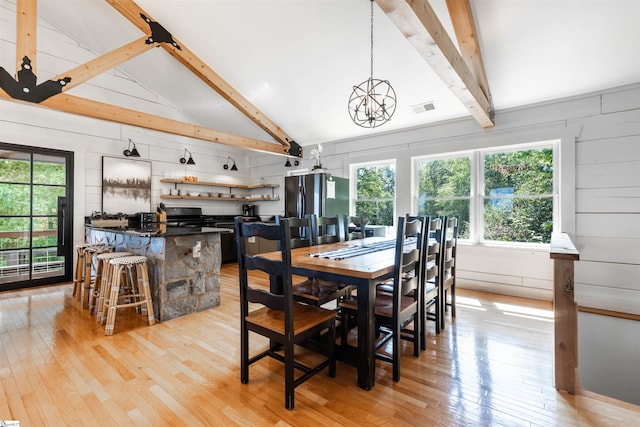 dining area featuring light wood-type flooring, wooden walls, and lofted ceiling with beams