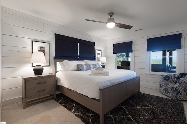 bedroom featuring wood walls, ceiling fan, and carpet