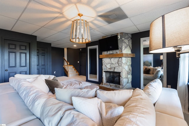 living room featuring a paneled ceiling and a stone fireplace