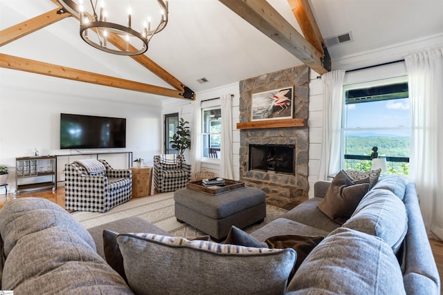 living room featuring plenty of natural light, an inviting chandelier, a stone fireplace, and beam ceiling