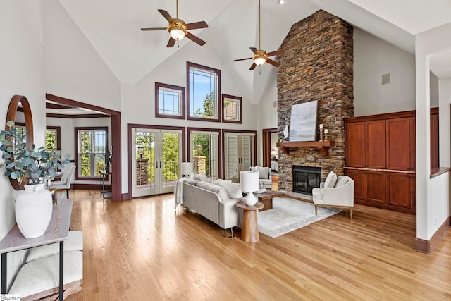 living room featuring high vaulted ceiling, ceiling fan, a fireplace, and light hardwood / wood-style flooring