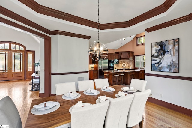 dining space with a tray ceiling, an inviting chandelier, light hardwood / wood-style floors, and crown molding