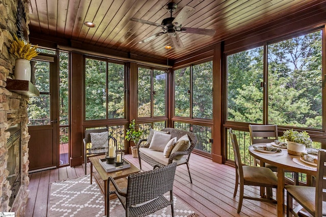 sunroom with ceiling fan, a wealth of natural light, a fireplace, and wooden ceiling