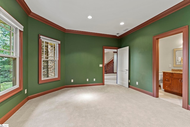 empty room with ornamental molding, a healthy amount of sunlight, and light colored carpet