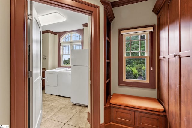 interior space with ornamental molding, light tile patterned floors, and washing machine and clothes dryer