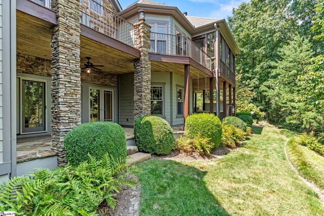 view of front of property with ceiling fan, a balcony, and a front yard