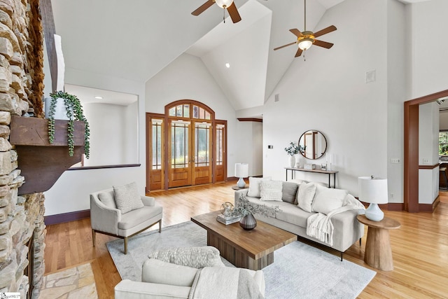 living room with light wood-type flooring, a fireplace, high vaulted ceiling, and ceiling fan